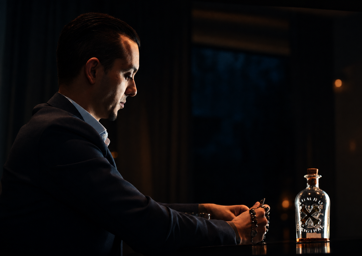 Donker portret van een man aan een tafel met een Wisky fles tijdens een cinematic fotoshoot